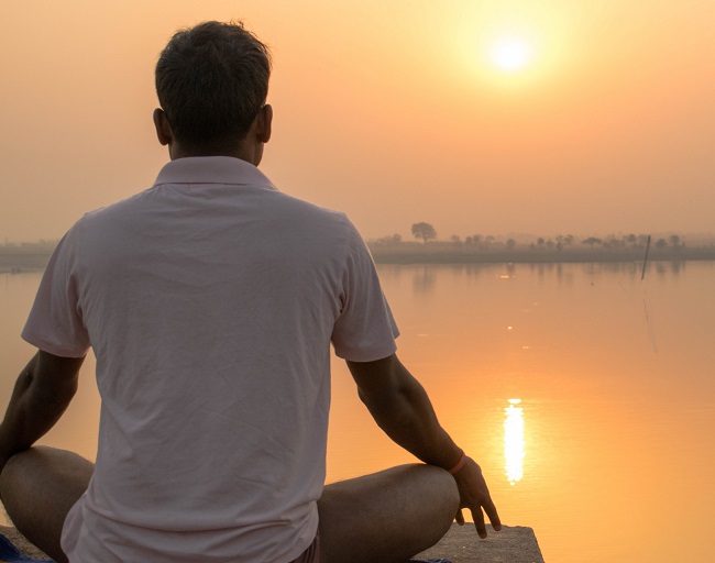 A man practices yoga and meditation in sunrise