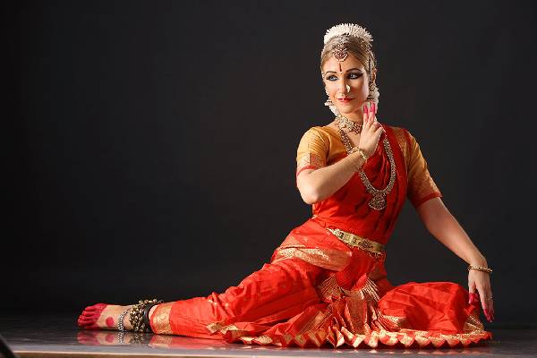 :Image of a girl performing Bharatanatyam pose showing Mudras in hand in black background